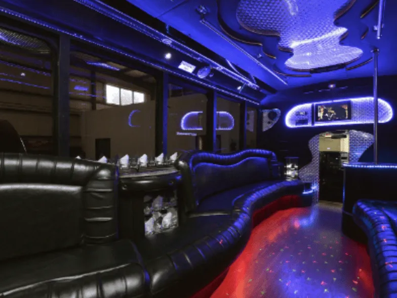 Black GMC party bus interior with perimeter lounge seating, sofa-style seating and LED accent lighting for party bus rental