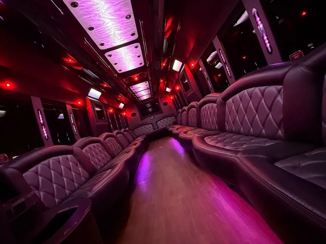 Freightliner Party Bus interior with perimeter lounge seating, LED ceiling lighting and wood-look flooring for party bus rental in North Attleboro, MA