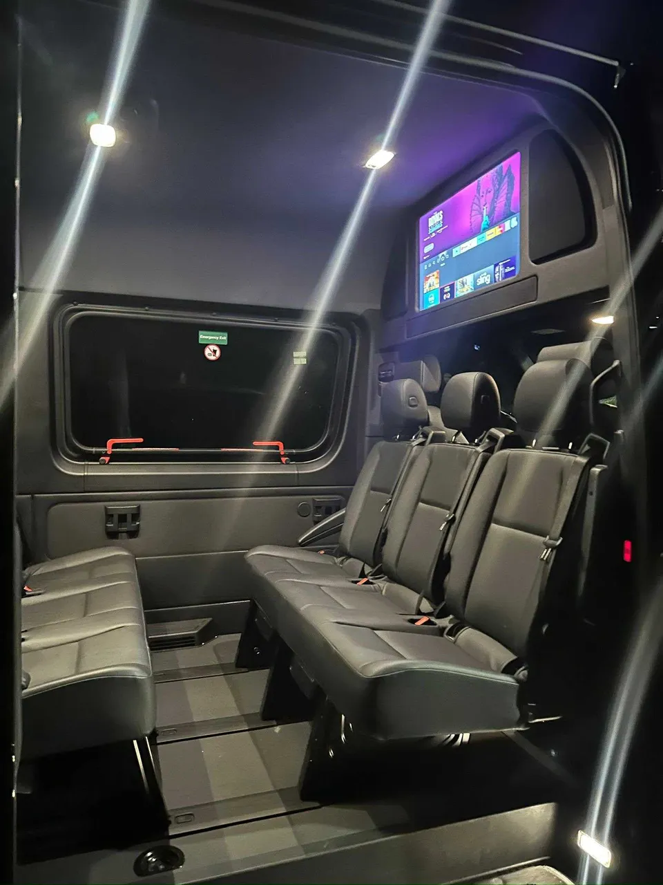 Mercedes-Benz Limousine Sprinter interior with TV screens and passenger seat belts for party bus rental in West Palm Beach, FL