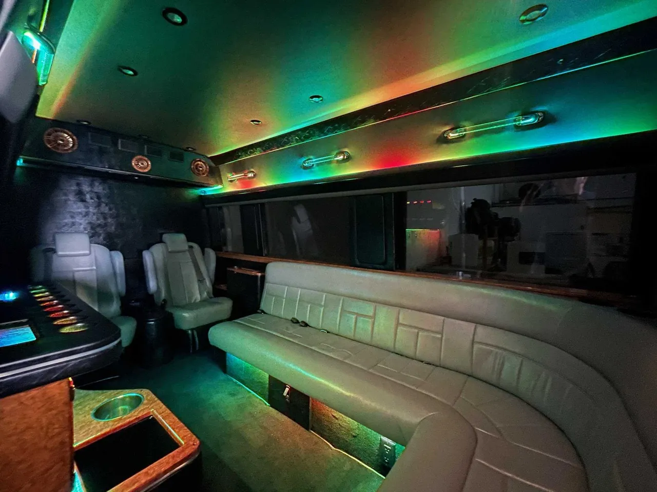Mercedes Sprinter Limo interior with sofa-style seating, captain's chairs and LED accent lighting for party bus rental in Columbus County, NC