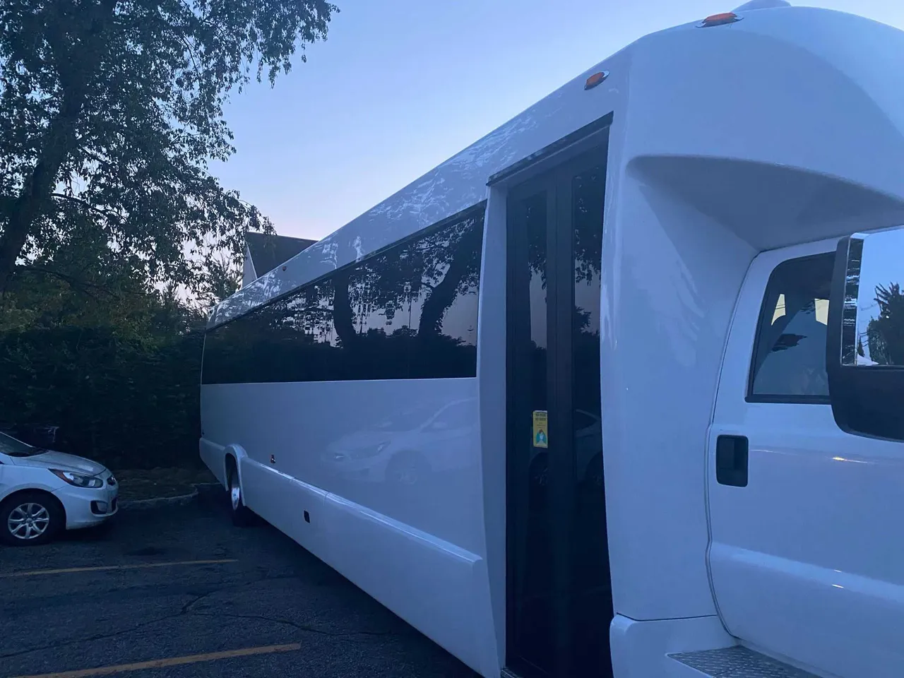 White 25 Passenger Party Bus exterior with tinted windows for party bus rental in Ozone Park, NY White 25 Passenger Party Bus exterior with tinted windows for party bus rental in Ozone Park, NY