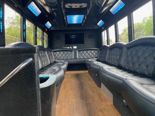 24 Passenger Party Bus interior with perimeter lounge seating, LED accent lighting and LED ceiling lighting for party bus rental in Mentone, CA