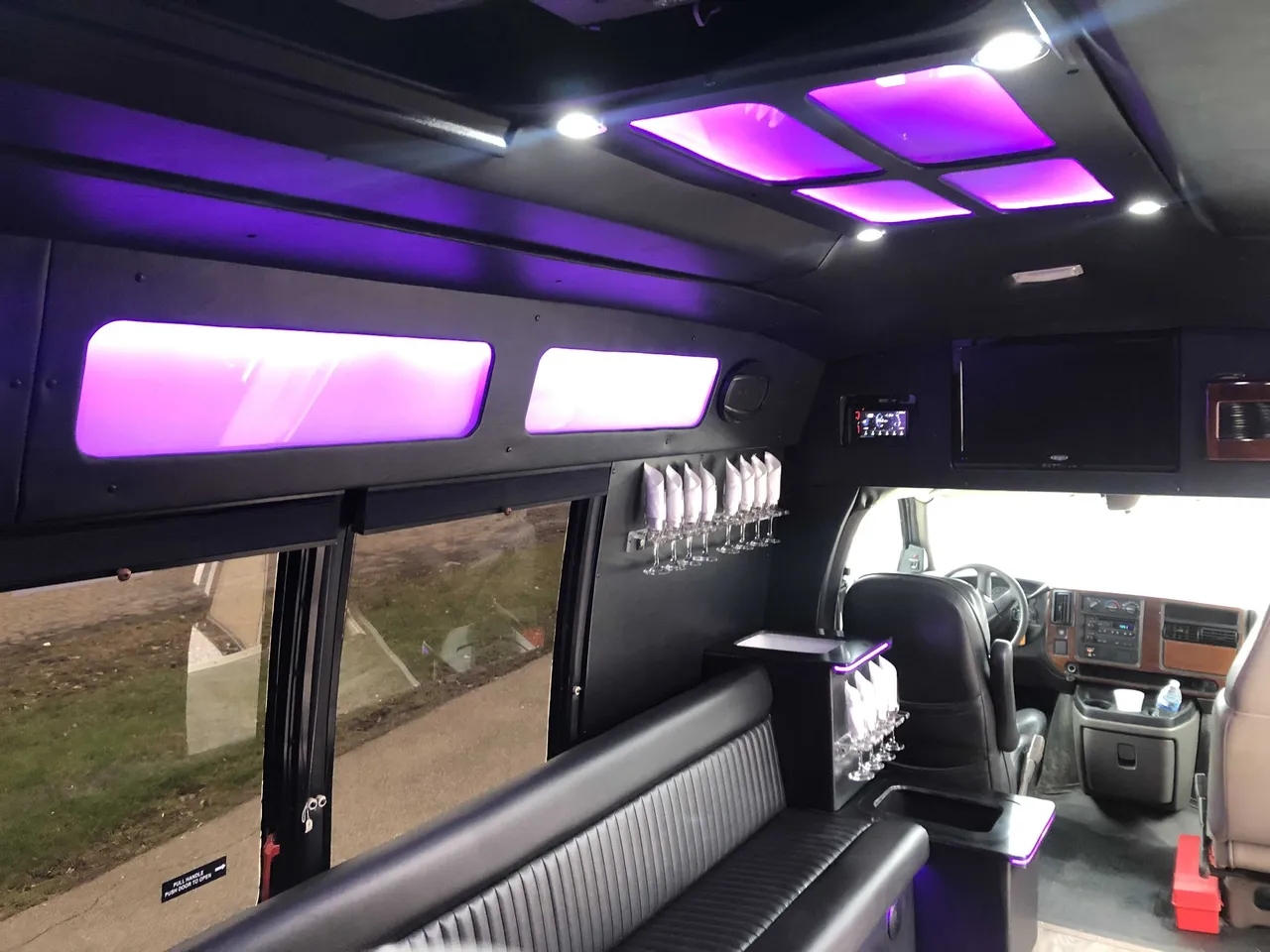 Small party bus interior with perimeter lounge seating, LED ceiling lighting and glassware holders for party bus rental in Union County, PA
