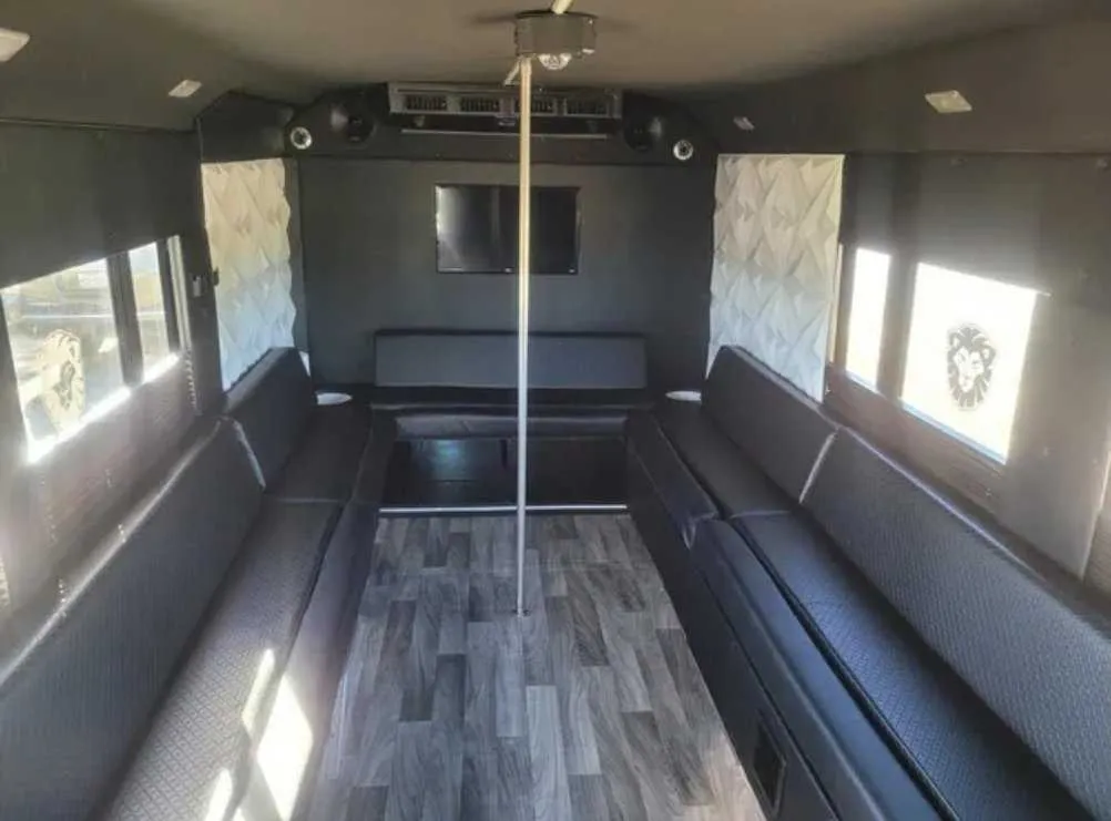 Tuxedo Party Bus Tuxedo Party Bus interior with perimeter lounge seating, wood-look flooring and TV screens for party bus rental